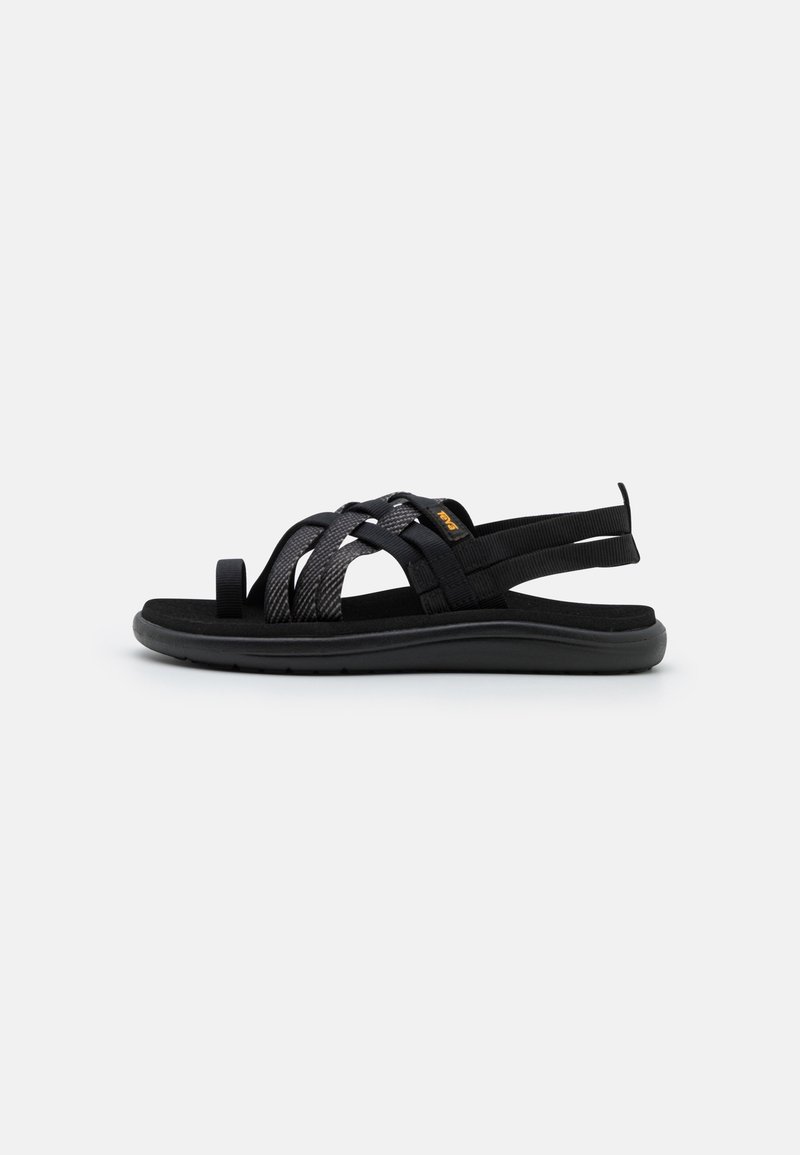Svarta sandaler med vävd remdesign, tillverkade av syntetiska material. Platt sula och öppen baksida för lätt påtagning.