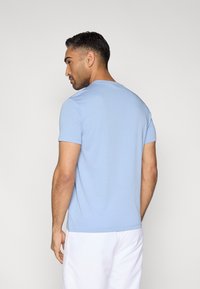 Camiseta azul claro de manga corta con cuello redondo, confeccionada con tela suave. La camiseta tiene un corte holgado y costuras planas, ideal para un uso casual.