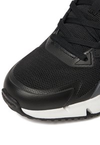 Must spordijalanõu hingava võrguga pealiskihil, sujuvate nahast detailidega ja kontrastse valge tallaga. Omaduseks on kaldus pealisdetailid ja tekstuuriga üksikasjad.