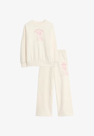 Ensemble en sweats couleur crème comprenant un sweat à capuche et un pantalon de jogging, avec un texte graphique rose "Crois en la magie" et un personnage de La Reine des Neiges sur les deux pièces.