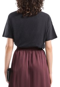 Czarny bawełniany t-shirt z krótkim rękawem, zestawiony z bordową satynową spódnicą z elastyczną talią i bocznymi plisami.