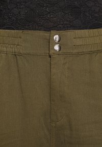 Olivově zelené látkové kalhoty s hladkou texturou, s plochým pasem, dvěma kovovými knoflíky a bočními kapsami pro praktičnost.