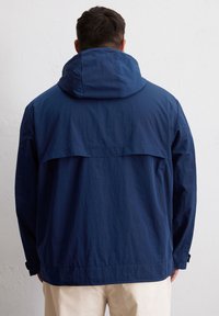 Helleblaue leichte Jacke mit einer festen Kapuze, lockerer Passform und einem Rückenteil mit Nahtdesign, aus glattem, strapazierfähigem Stoff.