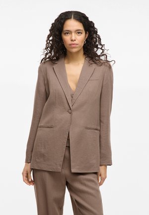Blazer en lin marron avec une coupe ajustée, revers crantés, fermeture à un bouton et deux poches avant. Texture lisse avec peu de plis.