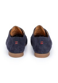 Scarpe in suede blu navy con suole in gomma marrone, con un accento rosso sul tallone e una fodera interna liscia. Design a taglio basso.