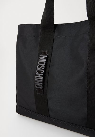 Mustmustest musta koti musta nailonist, millel on tugev riie, topeltkäepidemed ja küljes väljaulatuv "MOSCHINO" logo silt. Sile tekstuur ja struktuurne disain.