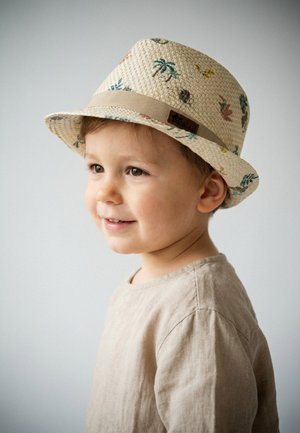 Smiling young boy wearing a beige shirt and a light-colored woven hat with small colorful tropical prints, looking slightly to the side.