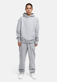 Grauer Hoodie mit einer Fronttasche und passender Jogginghose. Aus weichem Material gefertigt, bietet er eine lockere Passform und gerippte Bündchen.