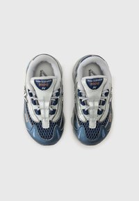 Blå och silverfärgade New Balance-skor med meshtopp, vadderad tunga och tonade snören. Har en rundad tå och texturerad sula.