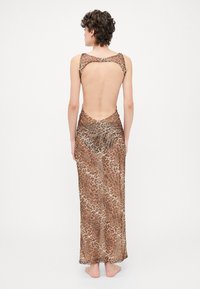Leopard print dress in lightweight fabric. Features a low back, sleeveless design, and ankle-length silhouette with ruched detailing.