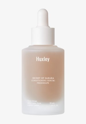 Huxley Conditioning Serum i en frostet glasdråbe flaske. Blød beige væske, hvid dråbepropp, og tekstdetaljer i sort og hvid.