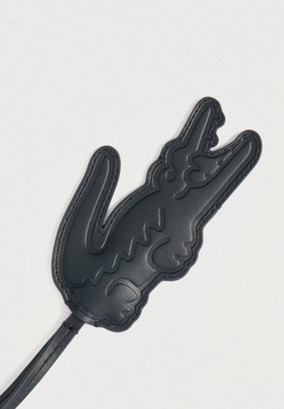 Porte-clés en cuir noir en forme de main faisant le geste "rock on" ou "cornes du diable", avec des détails cousus.