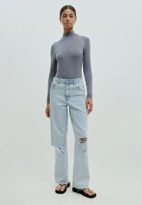 Grijze lange mouw bodysuit, lichtblauwe versleten jeans met rafelige zoom, gedragen met zwarte teenslippers. Eenvoudig ontwerp en zachte texturen.