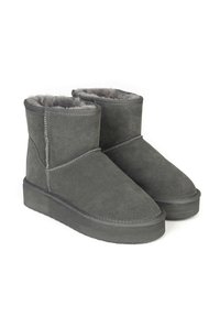 Botas de tobillo de ante gris con un interior suave y peludo, puntera redondeada y suelas de goma planas. Acentos de costura a lo largo de las costuras.