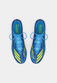 Blue soccer shoes with bright yellow accents, featuring a sleek design, textured upper, and matching blue shoelaces.
