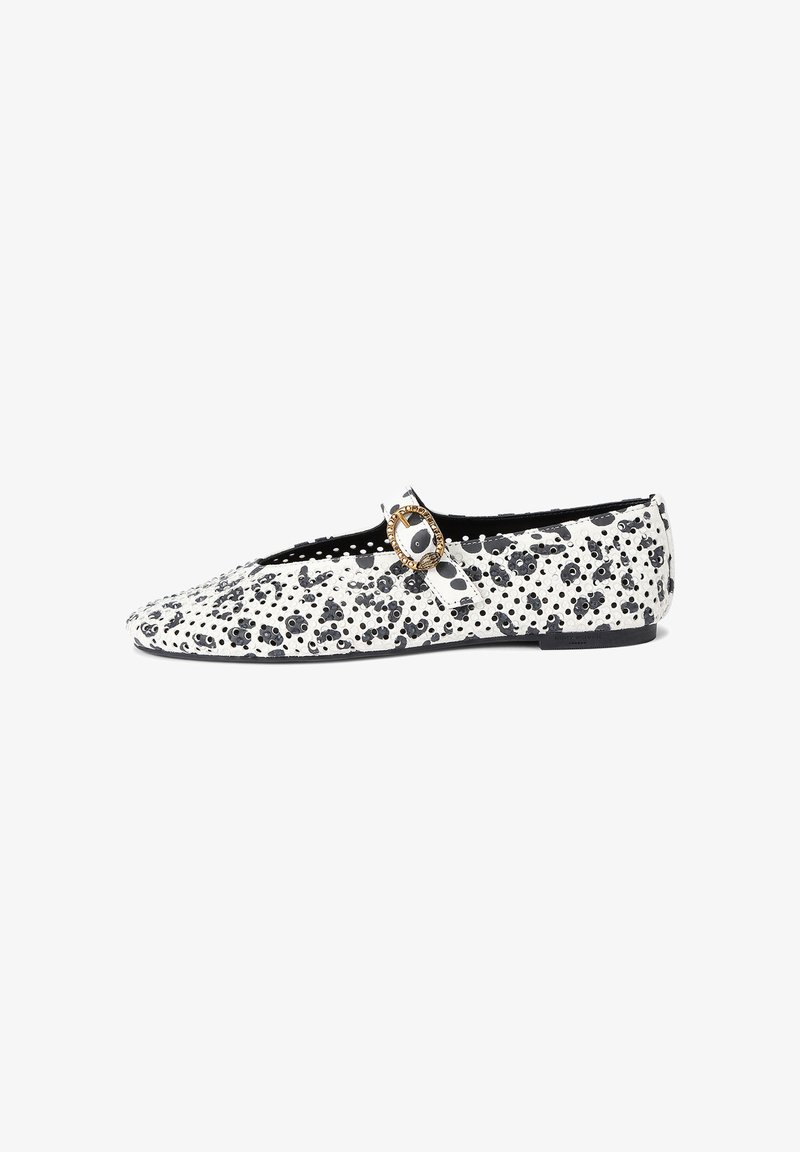 Chaussure Mary Jane plate, noire et blanche à pois, avec surface texturée et boucle dorée sur fond blanc.