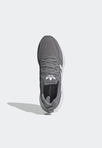 Gray knitted Adidas sneaker with white sole and logo, viewed from above on a plain light background casting a shadow.