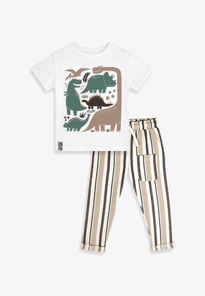 T-shirt blanc à manches courtes avec des dinosaures verts et marron, associé à un pantalon beige, noir et blanc à rayures verticales, taille élastique et poche.