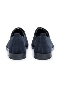 Chaussures en suede bleu marine avec une semelle en caoutchouc noir plate, un talon bas et de courtes languettes pour un enfilage facile. Design minimaliste, sans motifs visibles.