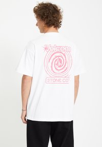 White cotton t-shirt featuring a large pink graphic on the back, including text and a spiral design. Short sleeves and relaxed fit.