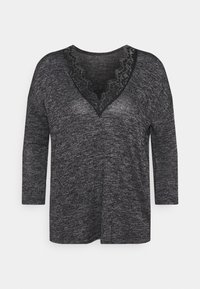 Svart och grå långärmad topp med V-ringning och spetsdetalj, tillverkad av ett mjukt, strukturerat tyg. Normal passform, krökt fåll.