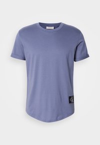 Light purple cotton t-shirt with short sleeves, a rounded neck, and a black branded tag on the lower left side. Smooth texture.