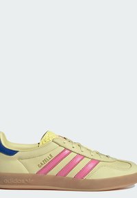 Svijetložuti tenisici s ružičastim i crvenim prugama, teksturiranim detaljima na jeziku i plavom petom. Prozirna gumena potplat.