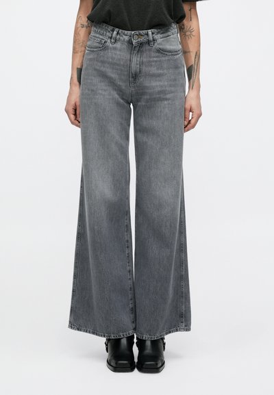 Jean gris en denim à jambes larges avec une taille haute et des passants pour ceinture. Présente des coutures latérales prononcées et une texture légèrement délavée.