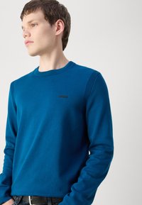 Sweatshirt albastru cu guler rotund, având accente ribbed pe umeri, cu un logo negru "BOSS" pe piept, fabricat dintr-un material moale.