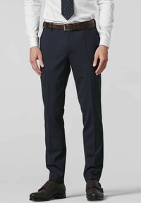 Marineblauwe broek met plooien aan de voorkant, gemaakt van een gladde stof, gecombineerd met een bruin leren riem en geweven donkerbruine schoenen.
