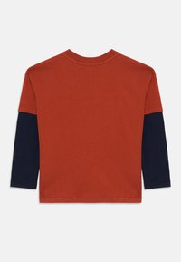 T-shirt rouge à manches courtes avec manches longues bleu marine. Tissu en coton doux, col ras du cou et design simple sans motifs ni accents.