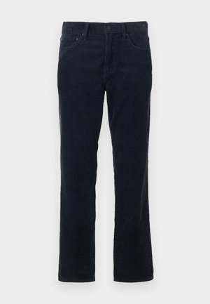 Mørk blå corduribukse med rett ben, med frontlommer, glidelås med knappelukking, og subtil vertikal ribbestruktur.