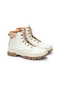 Botas de senderismo de piel blanca con acentos en tono marrón, diseño de cordones, cuello acolchado y suela de goma resistente con la marca Vibram para mayor tracción.