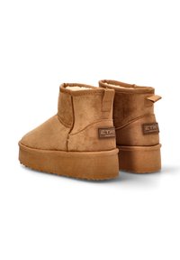 Botas de ante marrón hasta el tobillo con un interior suave, punta redondeada y suela texturizada. Presentan un lazo trasero y un detalle de marca en el costado.