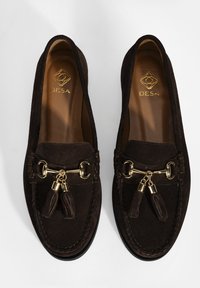 Bruine suède loafers met gouden hardware accenten en kwastjes, voorzien van gestikte details en een gladde binnenvoering.