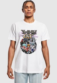 Biele bavlnené tričko s farebnou grafickou potlačou postáv z "Yu-Gi-Oh! GX" v kruhovom dizajne s detailným spracovaním.
