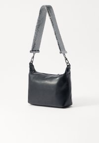 Black leather shoulder bag with a textured silver strap. Square shape, smooth surface, metal accents, and a zipper closure.