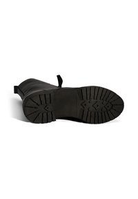 Schwarzer Lederstiefel liegt auf der Seite und zeigt eine dicke Gummisohle mit tiefem Profilmuster und Ziehschlaufen.