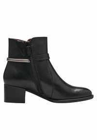 Bottine en cuir noir avec une fermeture éclair sur le côté, bout rond et petit talon carré. Présente une fine sangle avec un accent métallique. Texture lisse.