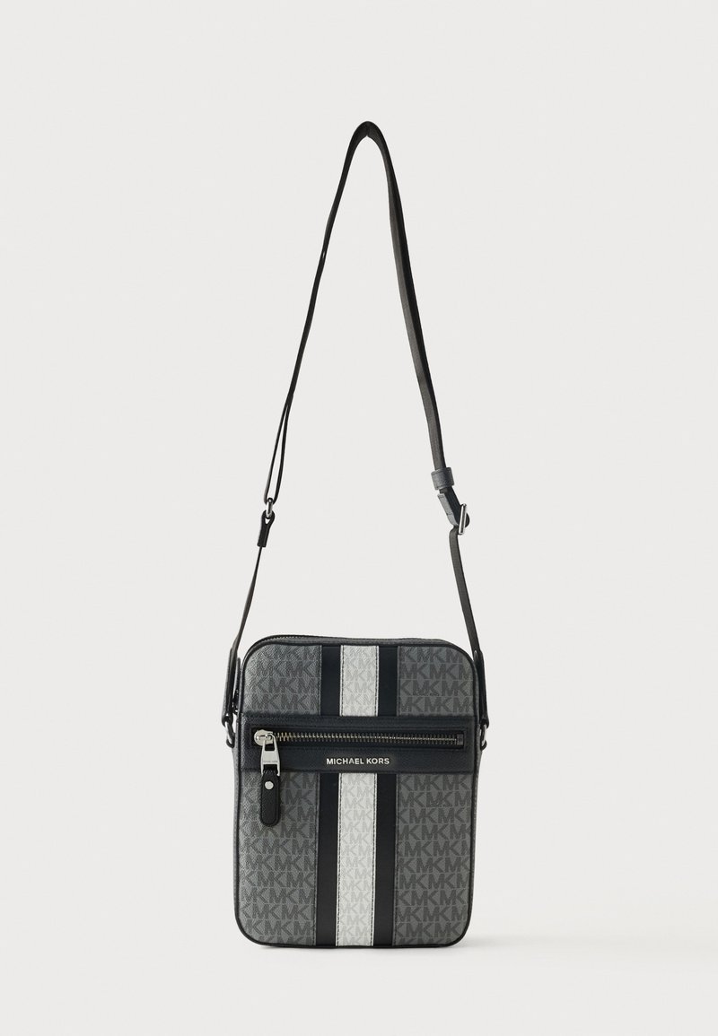 Γκρι τσάντα Michael Kors crossbody με κάθετες μαύρες και λευκές ρίγες, μπροστινή τσέπη με φερμουάρ και ρυθμιζόμενο ιμάντα ώμου.