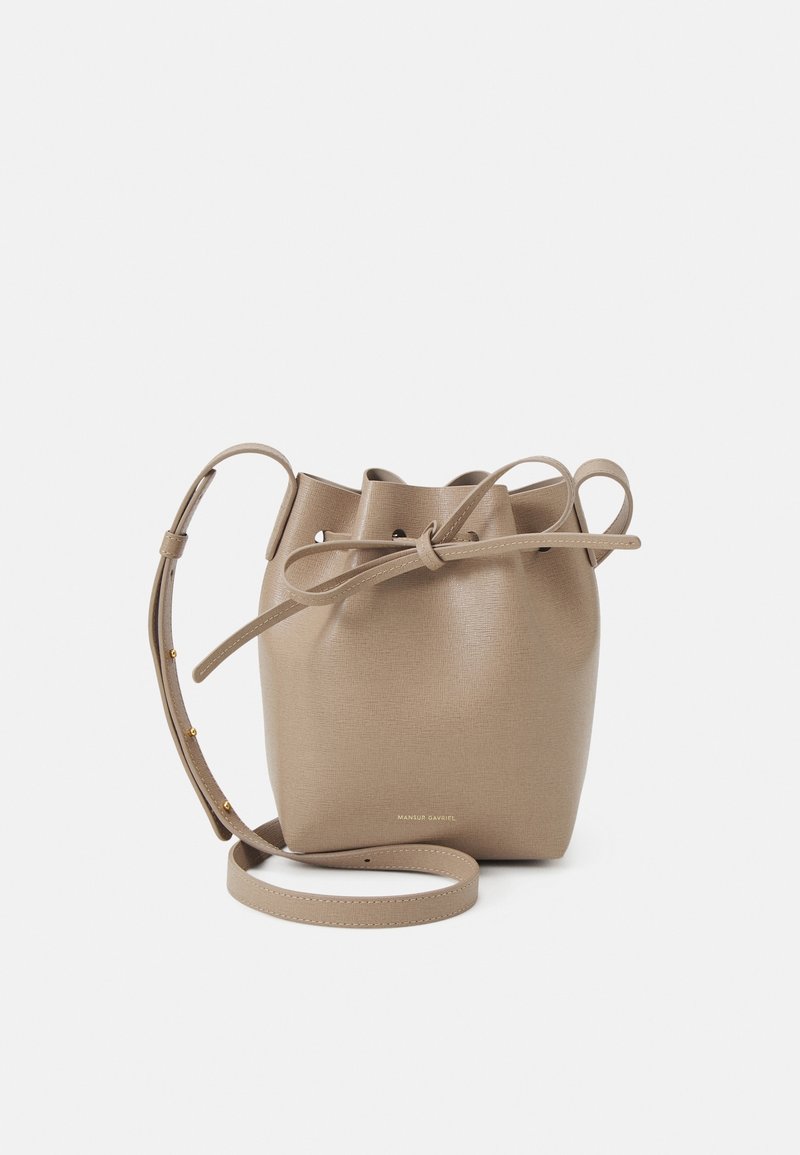 Sac seau en cuir beige texturé avec fermeture à cordon. Doté d'une fine bandoulière et de subtils accents en métal.