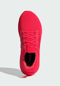 Leuchtend pinker Sportschuh mit einem Obermaterial aus Mesh, strukturierter Oberfläche und verstärkten Schnürsenkeln. Auf der Innensohle ist die Aufschrift „ULTRABOOST“ zu sehen.