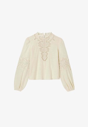 Blouse couleur crème avec manches longues bouffantes, ornée d'une broderie détaillée le long de l'encolure et des bords des manches. Tissu léger et texturé.