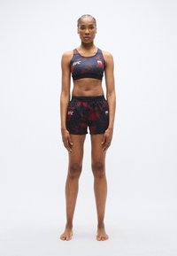 Ensemble brassière et short de sport UFC en rouge foncé et noir avec un design graphique. Comprend un tissu extensible et une taille élastique pour le confort.