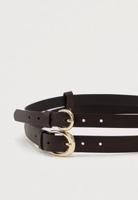 Brun læderbælte med to guldtonede spænder, med flere huller og en glat tekstur. Justerbar længde med et dobbeltremdesign.