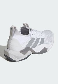 Hvid sportssko med øvre del af tekstureret mesh, grå striber og en tyk, formet sål. Har en trækflap bagpå for nem påtagning.