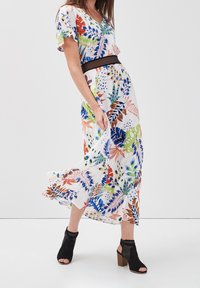 Robe maxi fleurie en tissu léger, dotée d'un col en V, de manches courtes et d'une taille cintrée avec une ceinture noire. Comprend des motifs de feuilles vibrants.