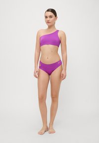 Purple bikini set featuring a one-shoulder top and high-waisted bottoms with side cutouts. Smooth texture and minimalist design.