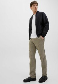 Black bomber jacket, white t-shirt, beige pants, black shoes. Simple design with a regular fit and zip closure on the jacket. Smooth texture.