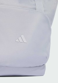 Mochila azul claro hecha de tela duradera, con una textura suave y un prominente logo blanco de Adidas. Diseño simple y rectangular.